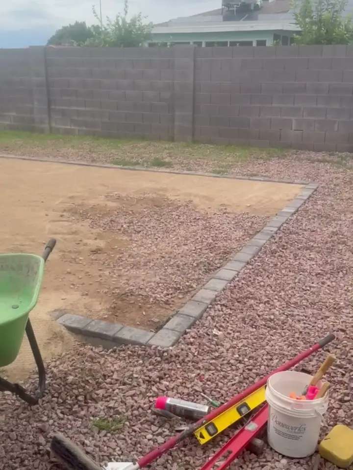 Before: compacted base inside a new paver border, with the plate compactor and wheelbarrow