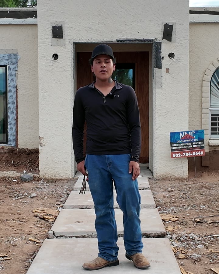 Gio, owner of Desert Edit Landscaping, standing on the stepping-stone path in front of a house with a dirt front yard